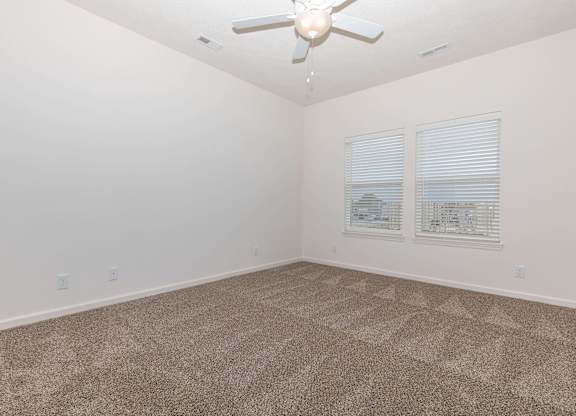 A room with a ceiling fan and carpeted floor.