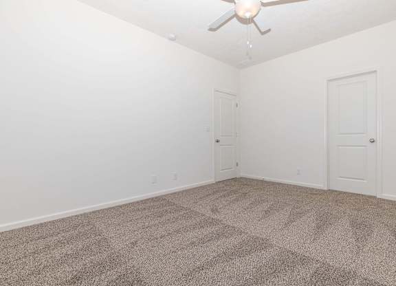 A room with a ceiling fan and carpeted floor.