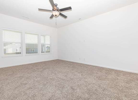 A room with a ceiling fan and carpeted floor.