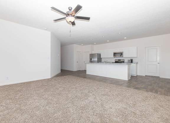 A room with a ceiling fan and a kitchenette.