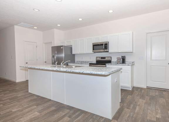 A kitchen with white cabinets and a marble countertop.