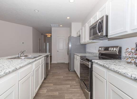 A kitchen with white cabinets and a marble countertop.