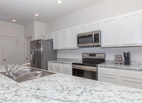 A kitchen with granite countertops and white cabinets.