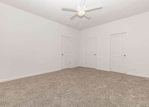 A room with a ceiling fan and carpeted floor.