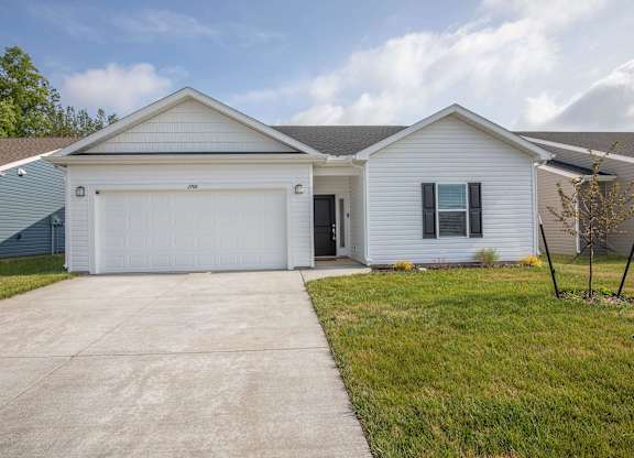 A white house with a garage door and a driveway.