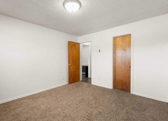 A room with two doors and carpeted floor.