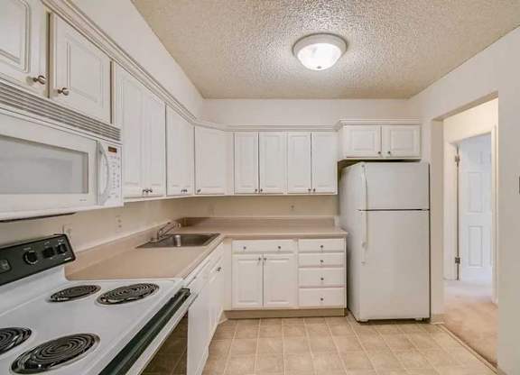 A kitchen with white cabinets and appliances.