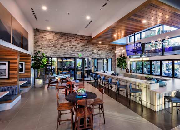 A modern bar area with a stone wall and wooden ceiling.