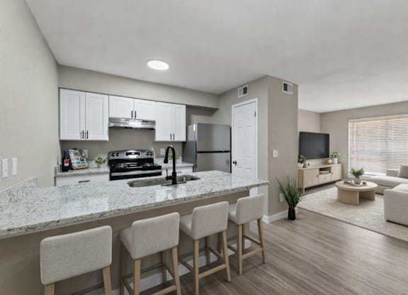 A modern kitchen with a marble countertop and bar stools.
