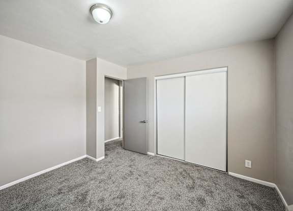 an empty room with white doors and carpet at Park at Fitzsimons Apartments, Colorado