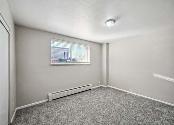 an empty living room with a window and carpet at Park at Fitzsimons Apartments, Aurora