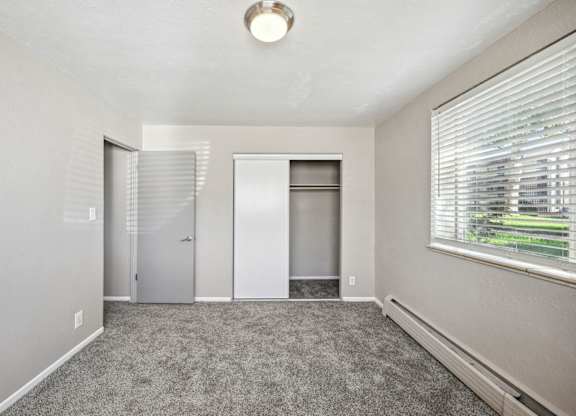 an empty room with carpet and a window and a closet at Park at Fitzsimons Apartments, Aurora, MO, 80011