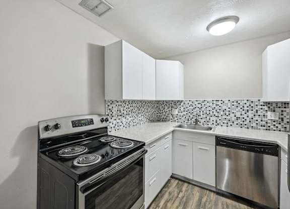 A kitchen with a black stove and white cabinets. at Park at Fitzsimons Apartments, Aurora 80011