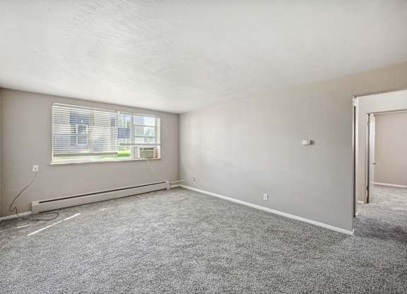 A room with a window and a carpeted floor. at Park at Fitzsimons Apartments, Aurora, MO