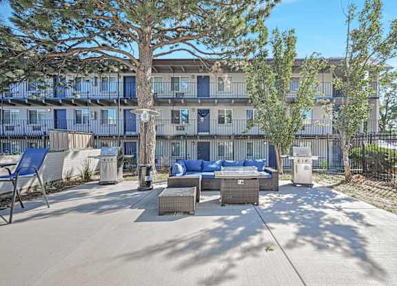a patio with furniture and trees in front of a building at Park at Fitzsimons Apartments, Aurora, MO