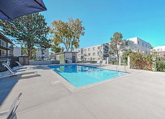a swimming pool with trees and buildings in the background at Park at Fitzsimons Apartments, Colorado, 80011