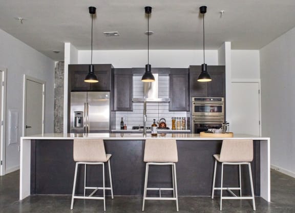 a kitchen with an island with three bar stools at The Audubon New Haven, Connecticut