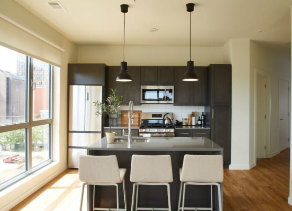 a large kitchen with black cabinets and a counter with four chairs at The Audubon New Haven, New Haven, CT, 06511