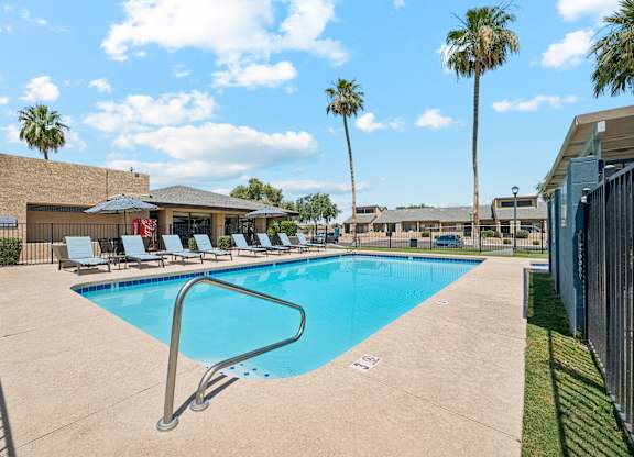 A large swimming pool surrounded by palm trees and lounge chairs.