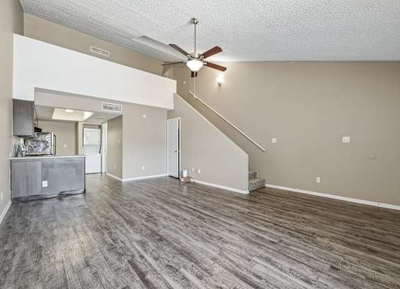 A spacious living room with a grey sofa and a wooden floor.