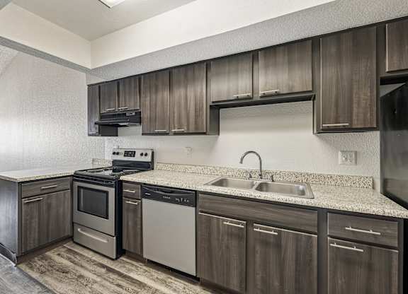 A kitchen with a stove, oven, dishwasher, and sink.