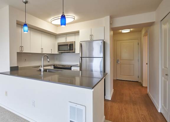 A kitchen with a stainless steel refrigerator and a microwave above the stove.