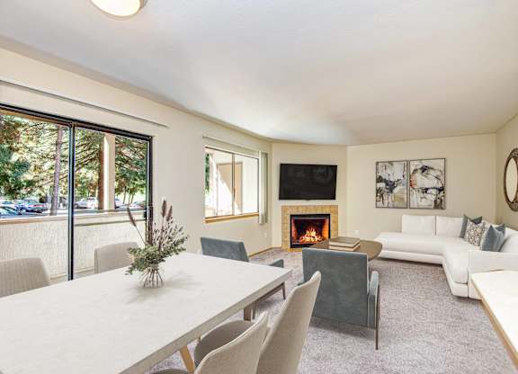 A living room with a fireplace and a dining table. at Autumn Village, Milton, WA, 98354