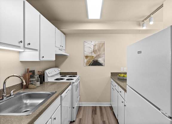A kitchen with white cabinets and a white fridge.