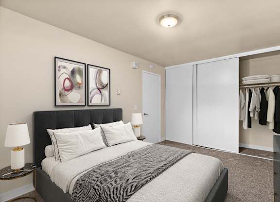 A bedroom with a bed, a nightstand with a lamp, and a closet with clothes.