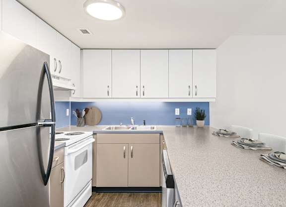 A kitchen with white cabinets and a blue backsplash.