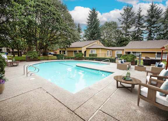 A swimming pool surrounded by a patio with chairs and a table.