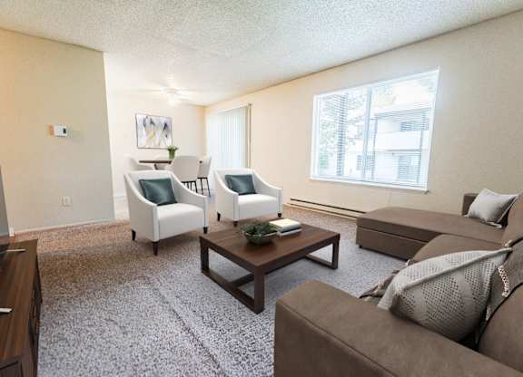 A living room with a brown couch, a white chair, and a coffee table.