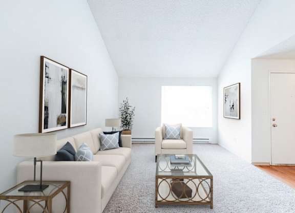 A living room with a white couch, a coffee table, and two framed pictures on the wall.