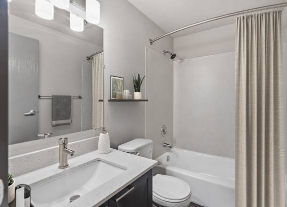 A modern bathroom with a white sink, toilet, and bathtub.