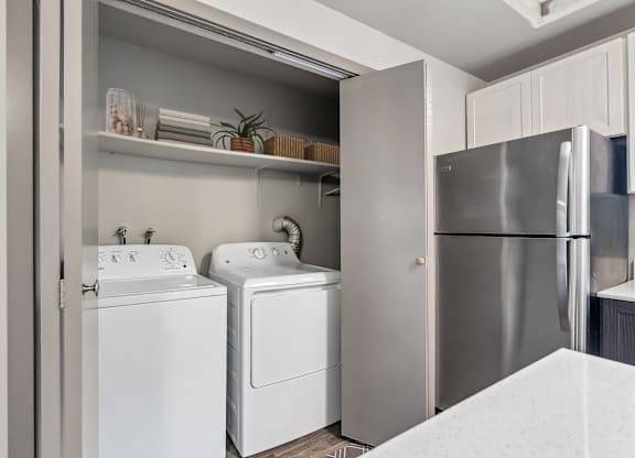 A modern kitchen with a refrigerator, washing machine, and dryer.