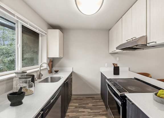 A modern kitchen with a sink, stove, and countertop.