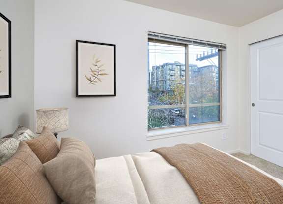 A bedroom with a large bed and a window overlooking a cityscape.