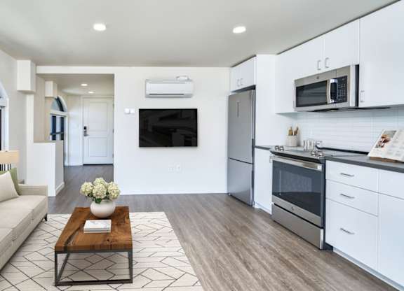 A modern kitchen with a breakfast bar and a living room area with a sofa.