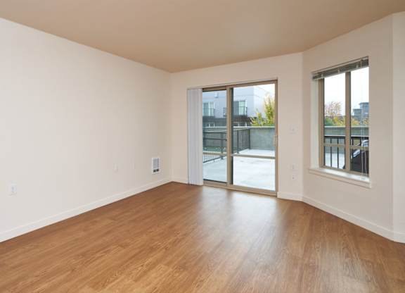 Empty room with wooden floors and sliding glass doors.