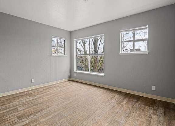 A room with wooden floors and two windows.