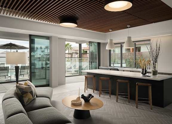 A modern living room with a grey sofa and a wooden ceiling.