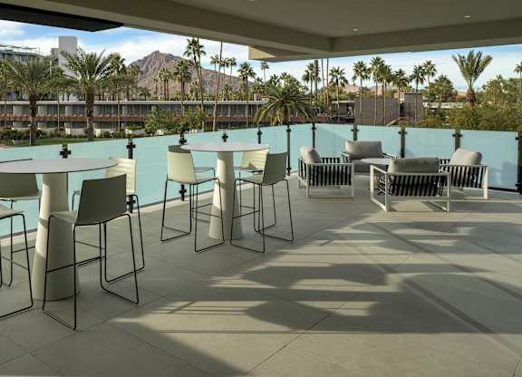 A patio with white chairs and a table with a blue wall.