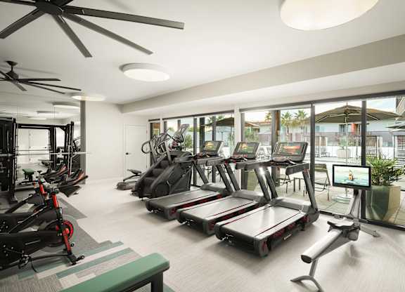 A gym with treadmills, exercise bikes, and a fan.