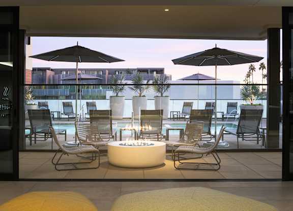 A modern outdoor seating area with a fire pit and chairs.