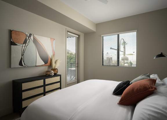 A bedroom with a large bed and a painting on the wall.