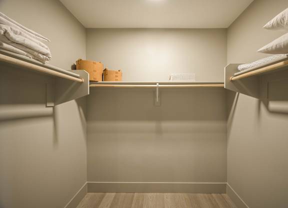 A small, empty closet with a wooden floor and white walls.