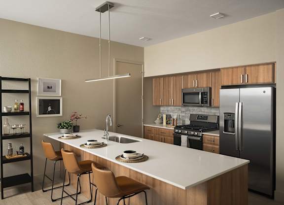 A modern kitchen with a white countertop and stainless steel appliances.