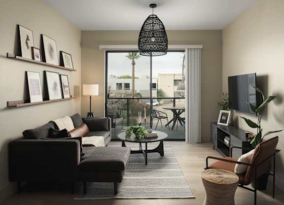A living room with a black couch, a coffee table, and a flat screen TV.