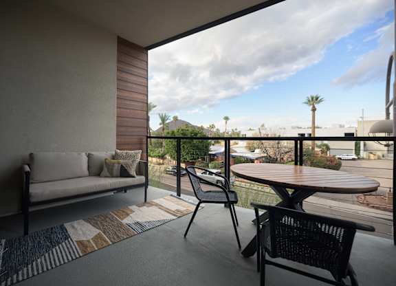 A balcony with a table and chairs overlooking a street.