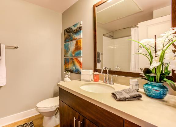 A bathroom with a white toilet and a wooden vanity with a blue vase on it.